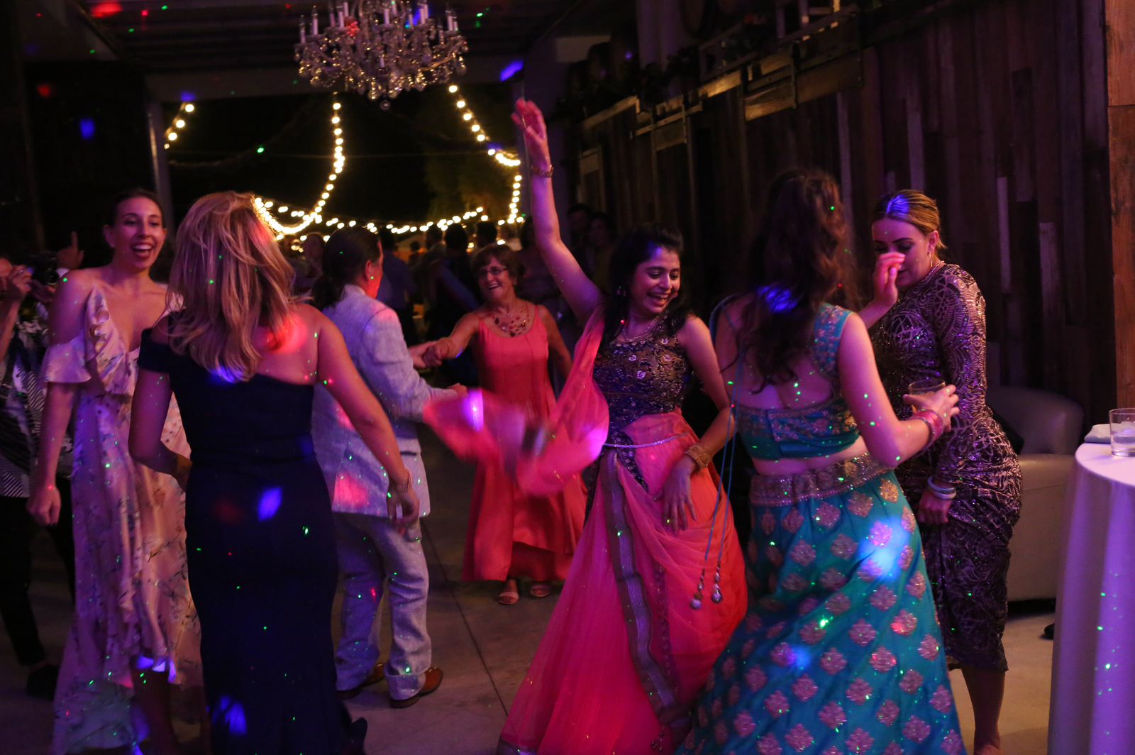 Guests dancing under a chandelier in bright light