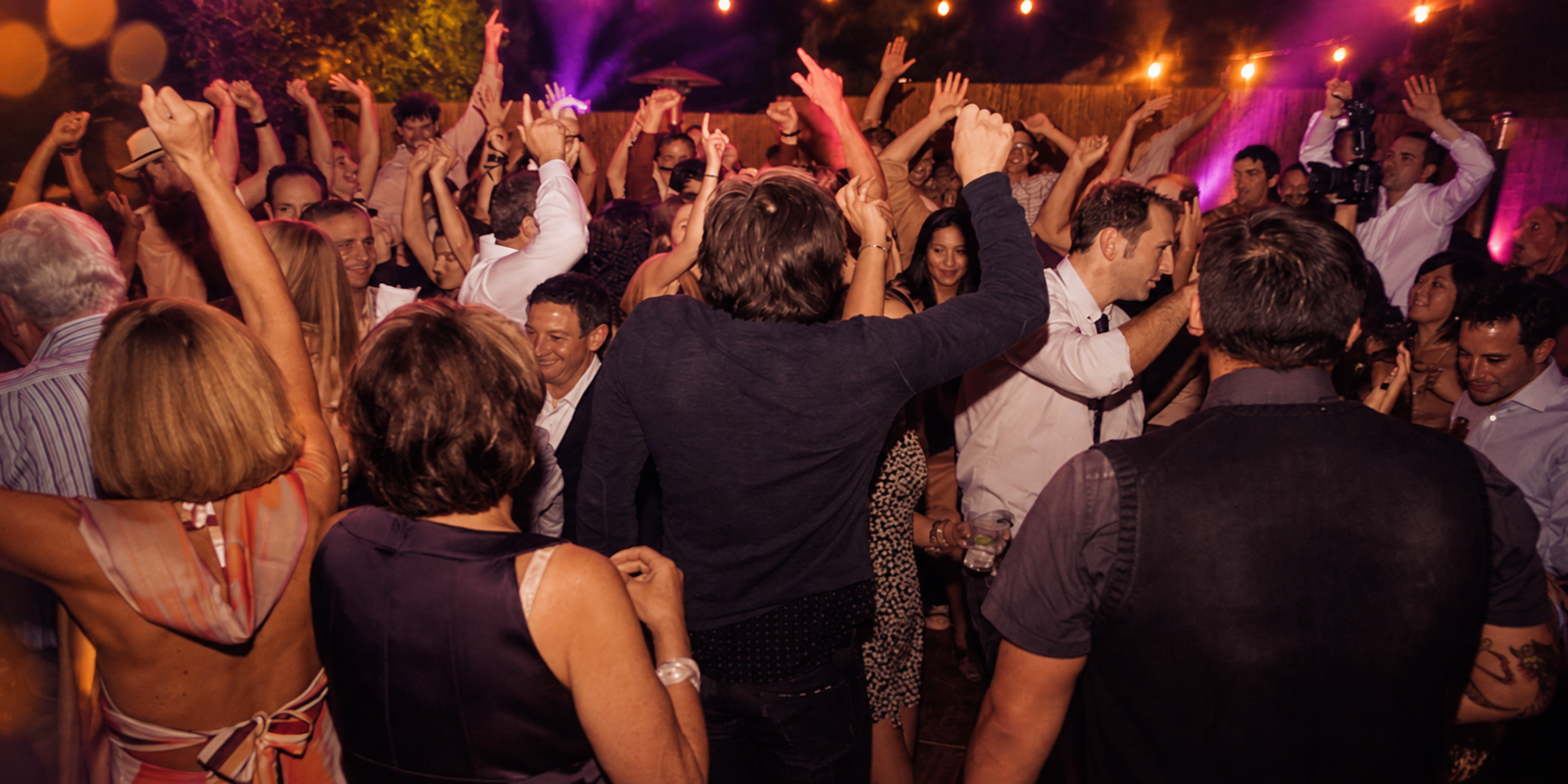 A packed outdoor dance floor with hands in the air